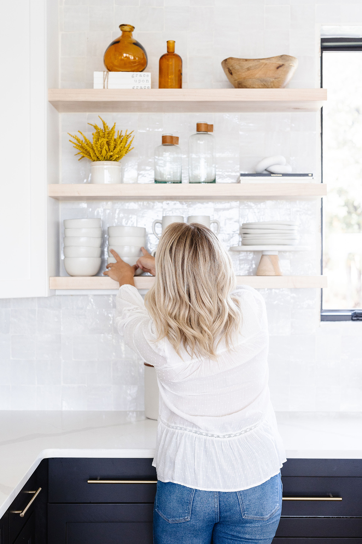 Woman reaching up to kitchen shelf