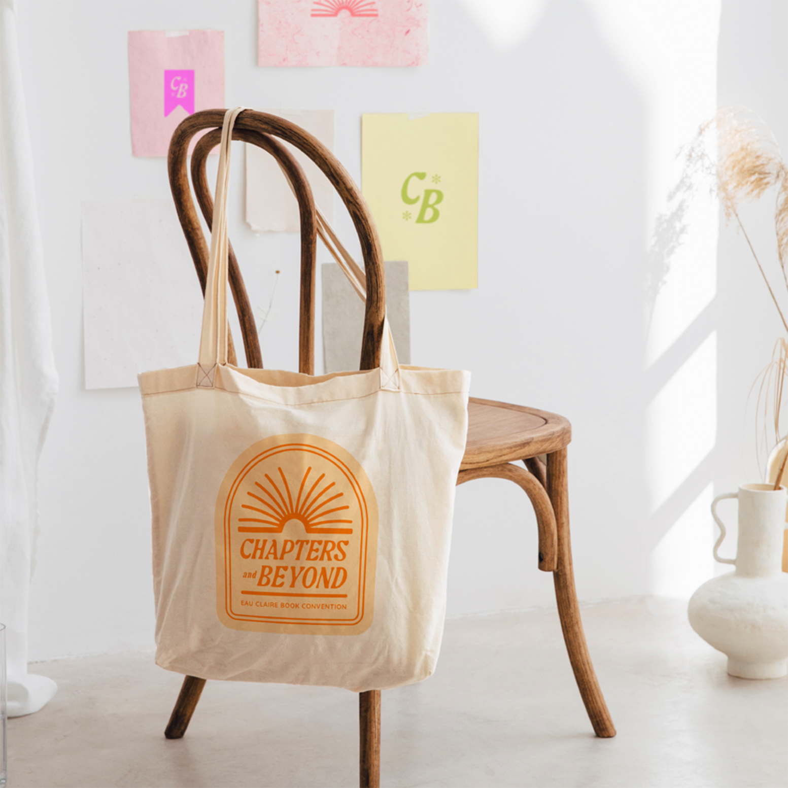 Tote bag hanging on wooden chair with bright orange Chapters and Beyond logo on it